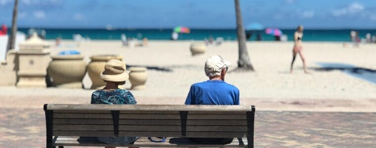 Man and woman sitting on brown wooden bench. 8 in 10 Would Not Sacrifice Holidays for an Early Retirement