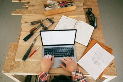 A person using a laptop while on the carpentry workbench. Consolidation in Hybrid Working Vacancies Indicates Shifting Balance of Power in Talent Market